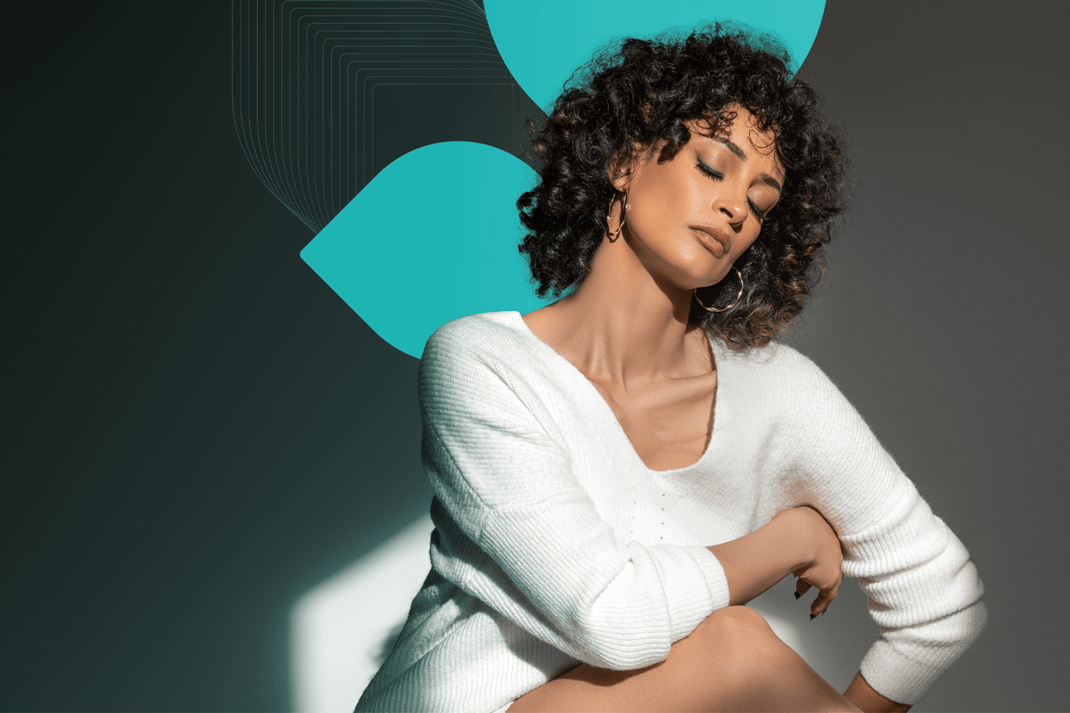 A woman with gorgeous curly hair poses in the sunlight, having taken the hair quiz to find out her hair type. 